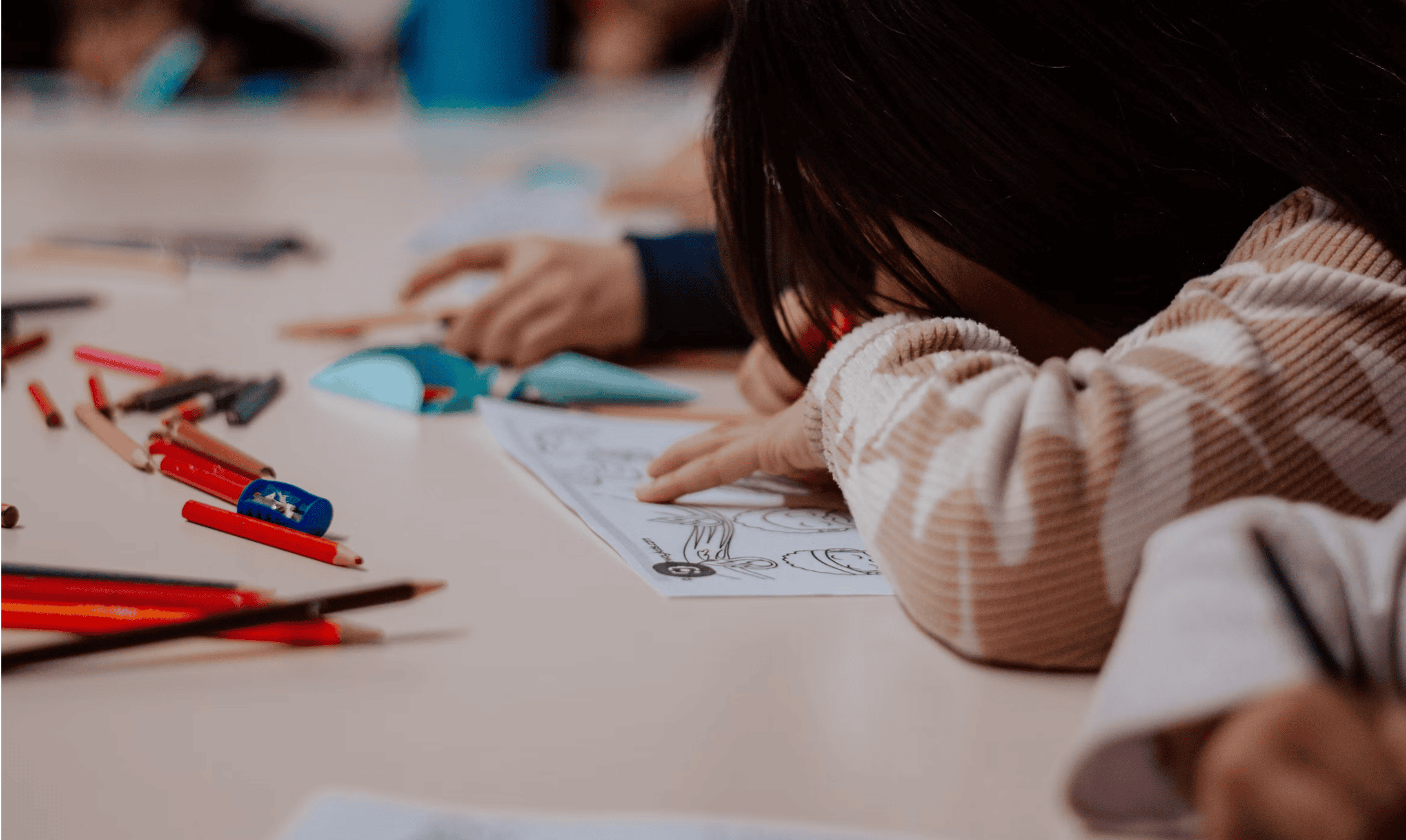 A child's hands pressing a pencil into a school worksheet, the paper dented and creased under the grip — the smell of pencil lead, eraser dust, and cheap classroom paper.